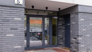 L’entrée d’un immeuble avec une porte en verre, une plaque portant le numéro « 5 » et une enseigne indiquant « Happy Home Apartments ».