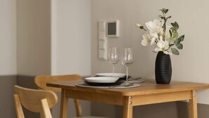 A dining table with two plates, two wine glasses, and a vase with white flowers. - Stylish Apartment in the Center | Air Conditioning and Balcony (Warszawa)