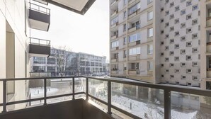 A high-rise apartment building with multiple balconies, large windows, and a view of a snowy street. - Stylish Apartment in the Center | Air Conditioning and Balcony (Warszawa)