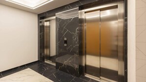 A modern elevator with marble walls and a metallic finish. - Stylish Apartment in the Center | Air Conditioning and Balcony (Warszawa)