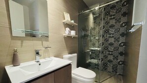 Ein modernes Badezimmer mit einem weißen Waschbecken, einer Toilette und einer Duschkabine aus Glas.