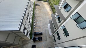 Un garaje de varios pisos con un edificio blanco a la izquierda y un edificio moderno a la derecha. Hay dos coches estacionados en el garaje.