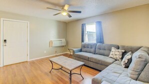 A living room with a ceiling fan, a sofa, a coffee table, and a door.