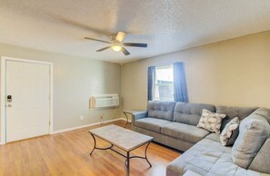 Un salon avec un ventilateur de plafond, un canapé, une table basse et une porte.