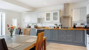 A modern kitchen with grey cabinets, a wooden countertop, and a dining area with a table and chairs.