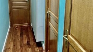 Un couloir étroit avec des portes en bois et un meuble blanc.