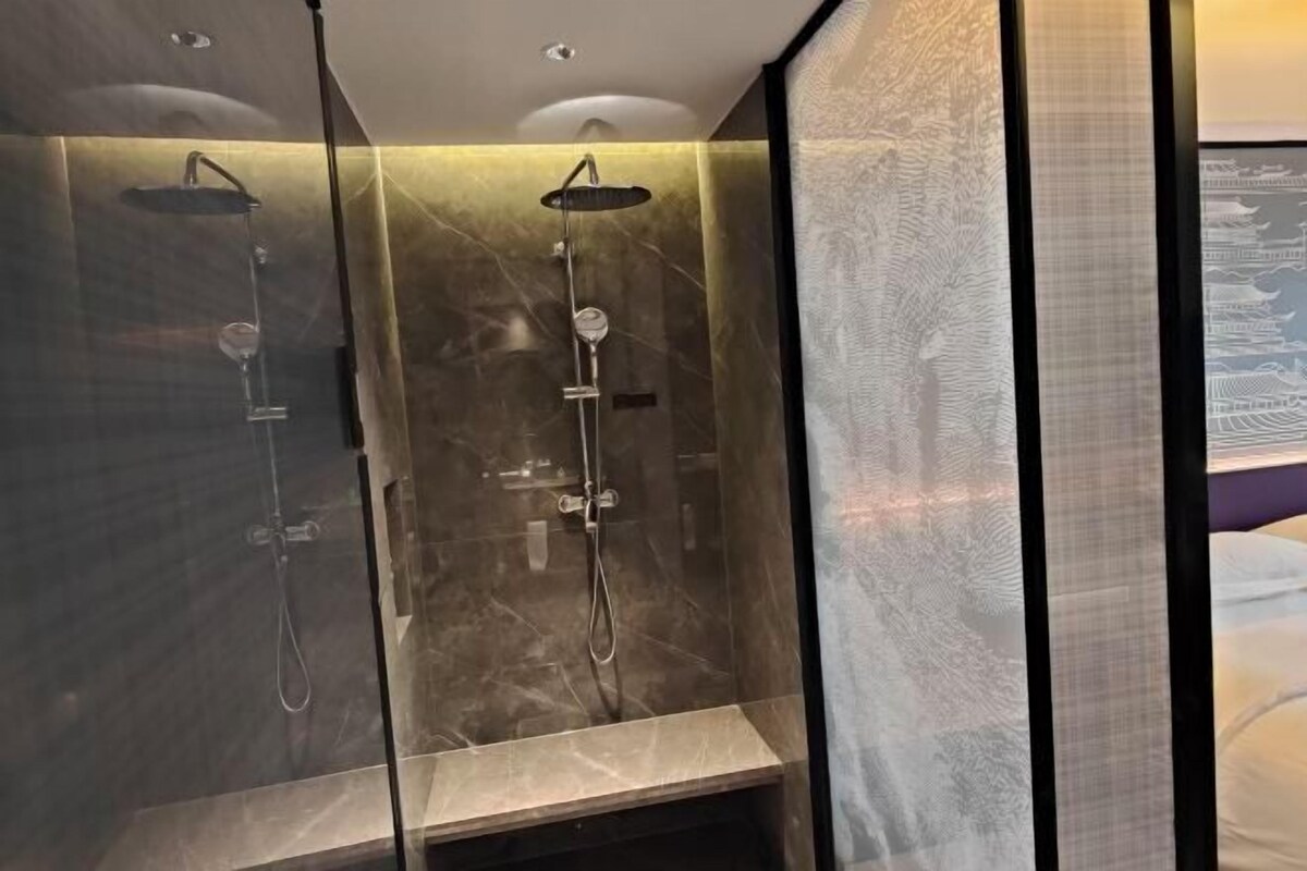 A modern bathroom with two glass-enclosed showers, marble walls, and a bench.