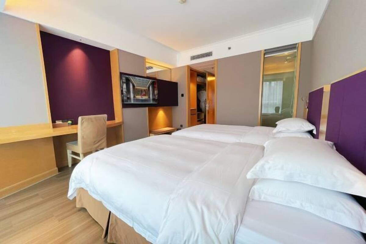 Et hotelværelse med en stor seng, et skrivebord, en stol og et fjernsyn.