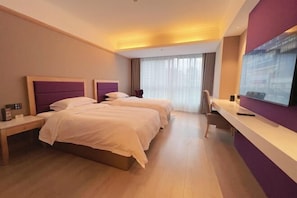 Ein Hotelzimmer mit zwei Betten, einem Schreibtisch, einem Stuhl und einem großen Fenster mit Vorhängen.