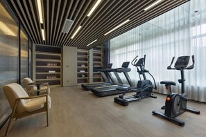 Een moderne sportschool met fitnessapparatuur, een zithoek en een groot raam.