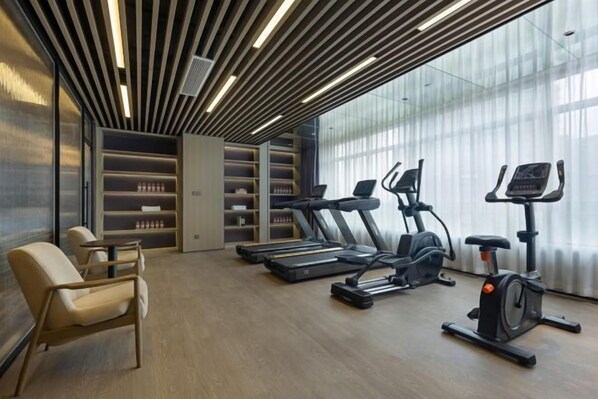 A modern gym with exercise equipment, a seating area, and a large window.