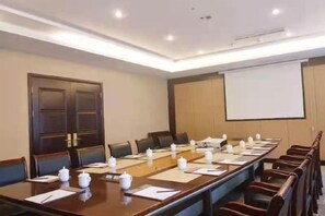 A conference room with a long table, chairs, a projector screen, and a whiteboard.