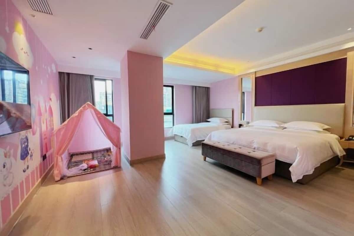 Et hotelværelse med et pink legetelt, to senge, et stort vindue og et moderne design.