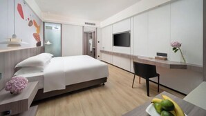 A modern hotel room with a bed, a desk, a TV, and a small dining area. - Maison New Century Hotel Wucheng Jinhua (Jinhua)
