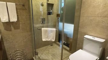Une salle de bain moderne avec une douche à parois de verre, des toilettes blanches et un porte-serviettes.