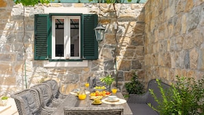 Un bâtiment en pierre avec une table dressée pour le petit-déjeuner, comprenant du pain, des fruits et du jus.