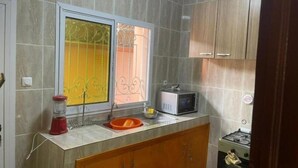 Una cocina con encimera de mármol, microondas integrado y armarios de madera.