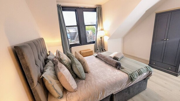 Een slaapkamer met een bed, een raam, een lamp en een kledingkast.