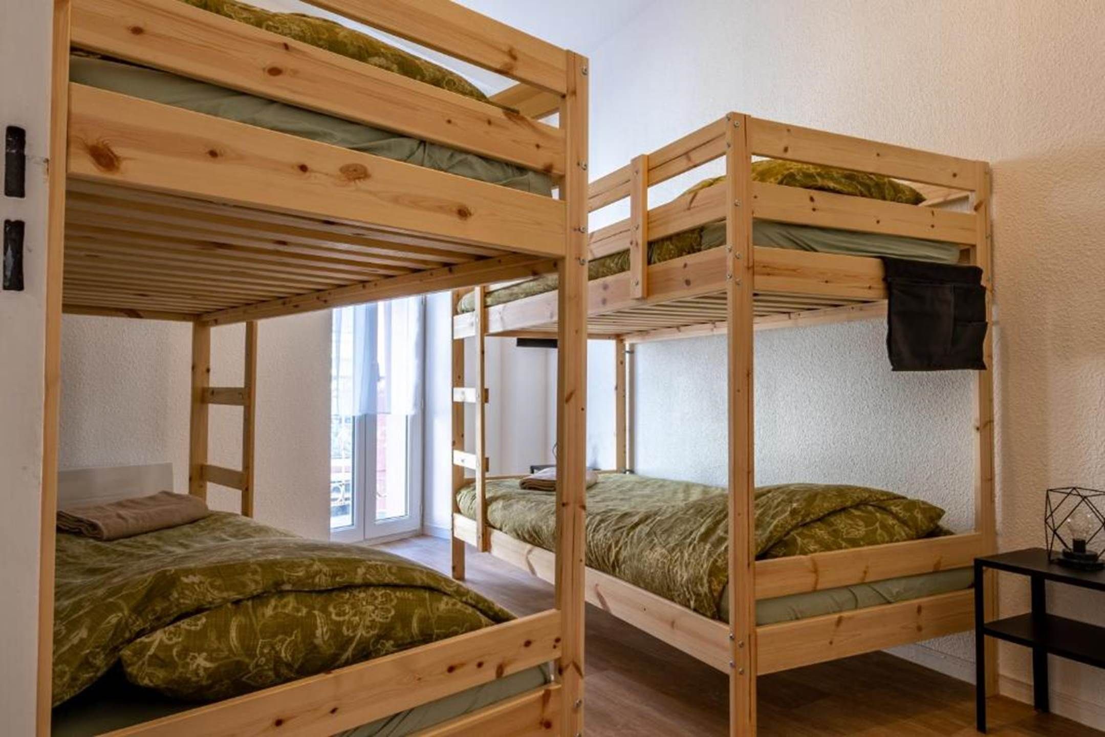 A room with bunk beds, a window, and a small table.