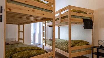 A room with bunk beds, a window, and a small table.