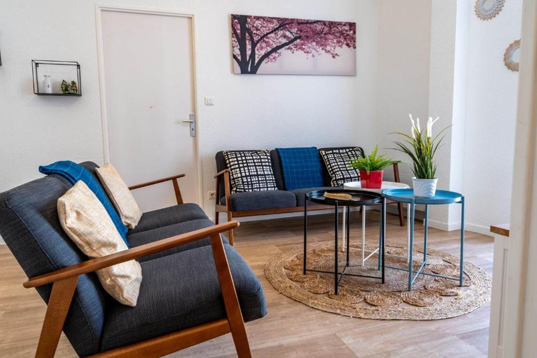 A living room with a sofa, a chair, a small table, and a potted plant.