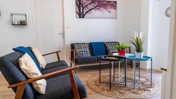 A living room with a sofa, a chair, a small table, and a potted plant.