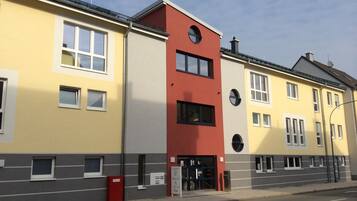 Ein mehrstöckiges Gebäude mit einer gelben Fassade, einem roten Abschnitt und einem grauen unteren Teil.