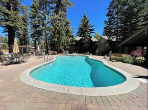 Relax by the oval-shaped pool surrounded by lush trees and comfortable lounge seating.