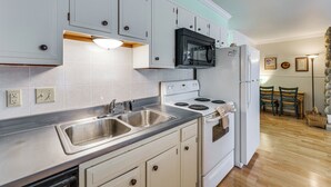 A kitchen with white cabinets, a black microwave, a white refrigerator, a double sink, and a stove. - Main Street Red River Condo w/ Fireplace & Views! (Red River)