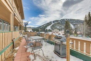 Une terrasse avec des sièges extérieurs et un barbecue, offrant une vue sur un paysage montagneux enneigé.