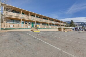 Un motel à plusieurs étages, doté d’un escalier central, d’un parking et surplombant un paysage montagneux.