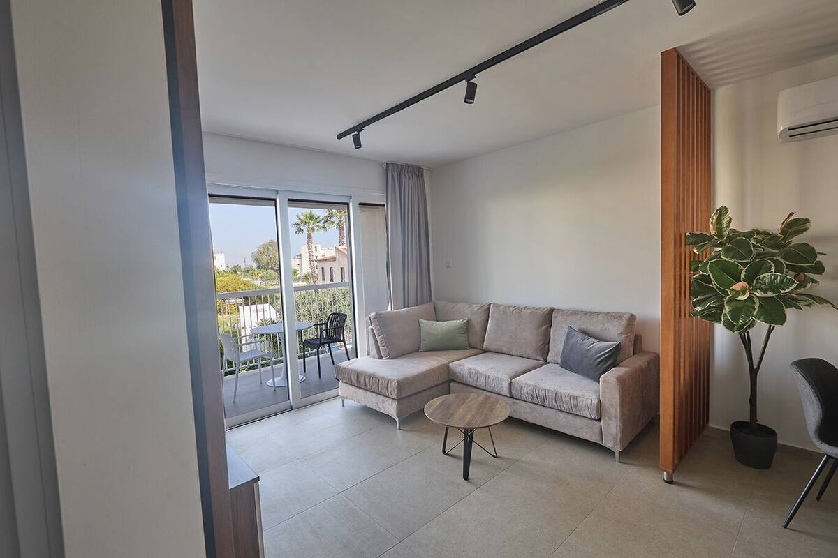 A modern living room with a beige sectional sofa, a round coffee table, and a potted plant.