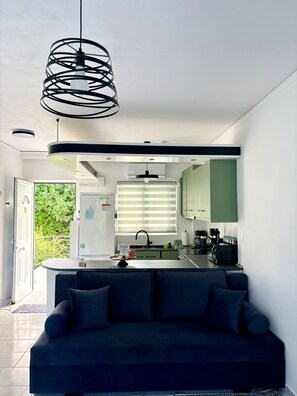 A modern kitchen with a central island, a built-in oven, and a coffee machine. - Sounio Golden View Villas (Lavreotiki)