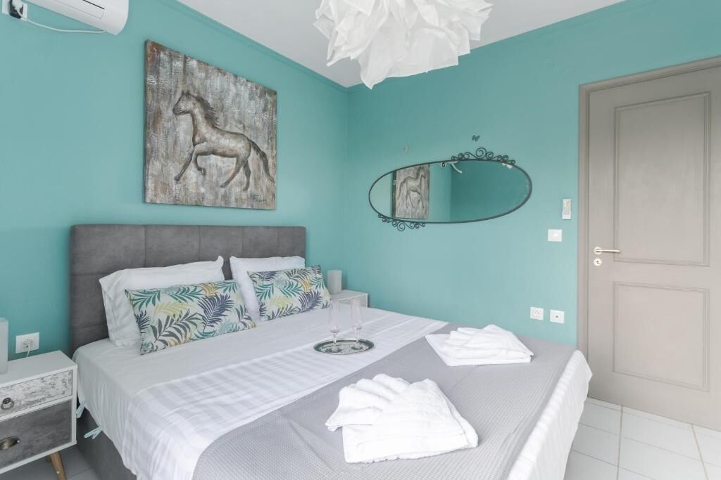 A bedroom with a bed, a nightstand, a wall-mounted mirror, and a door.