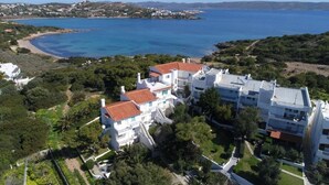 A coastal residential area with white buildings, a beach, and a clear view of the sea. - Sounio Golden View Villas (Lavreotiki)