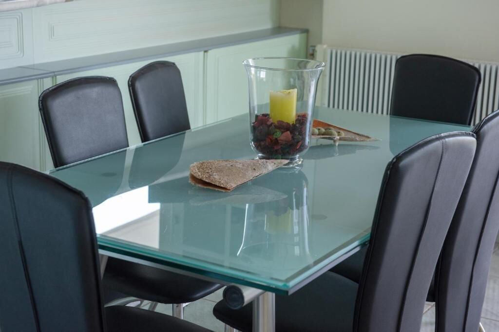 A conference table with a glass top, surrounded by black chairs.