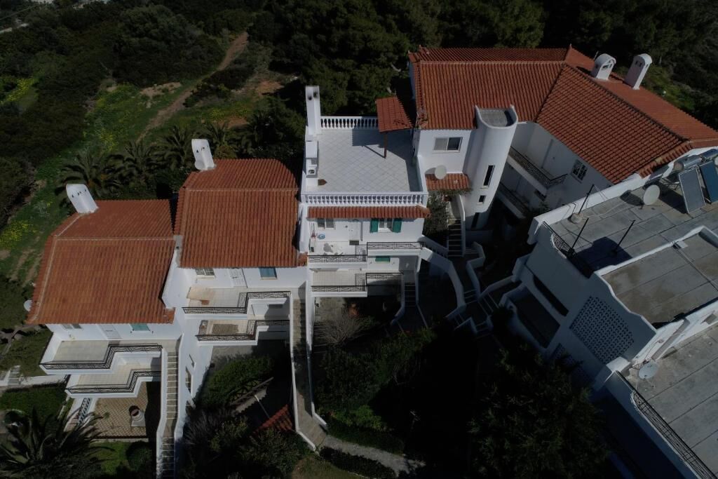 A modern multi-story building with a red-tiled roof, white exterior walls, and a central staircase.