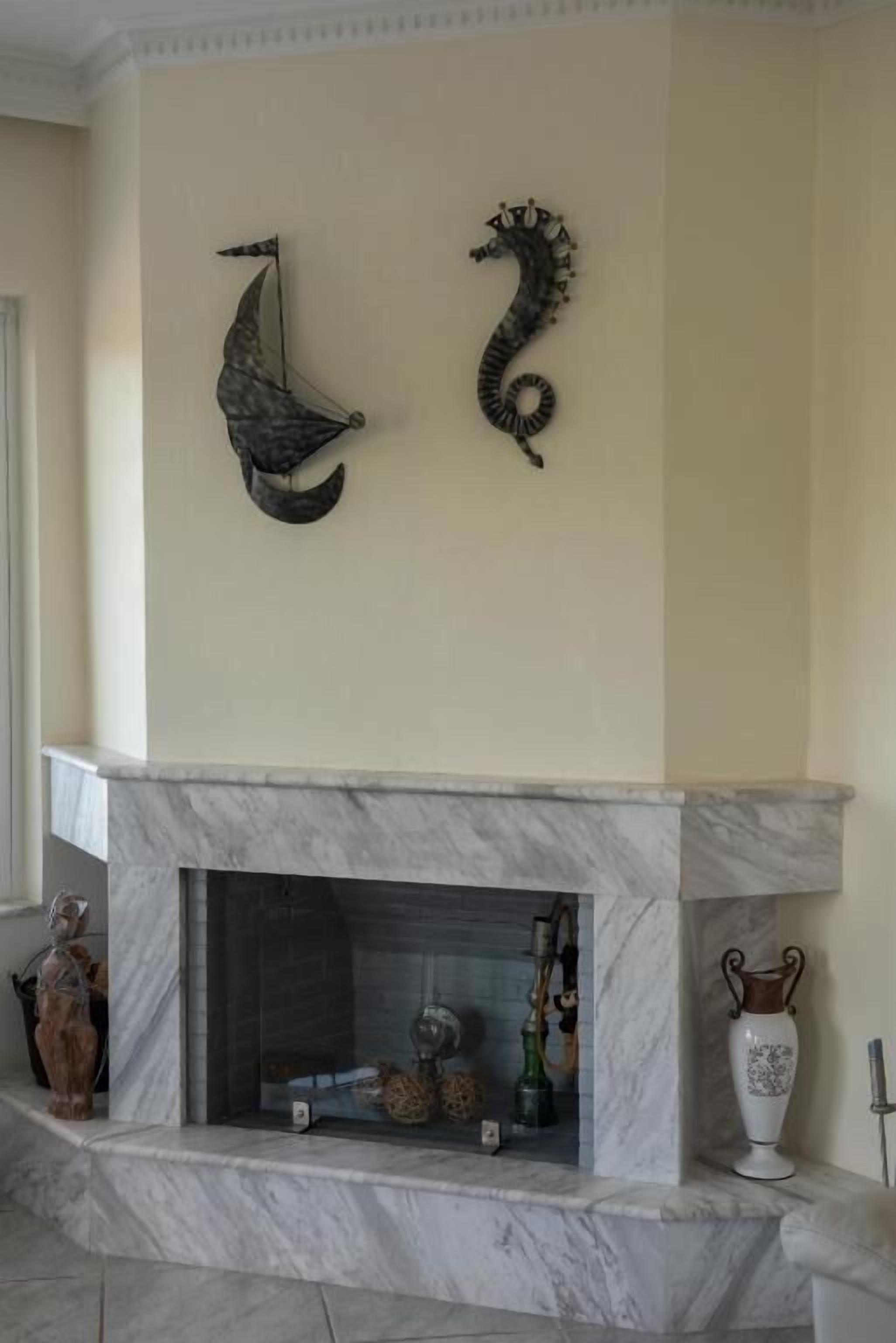 Une cheminée en marbre agrémentée d’objets décoratifs, notamment un vase et une sculpture.