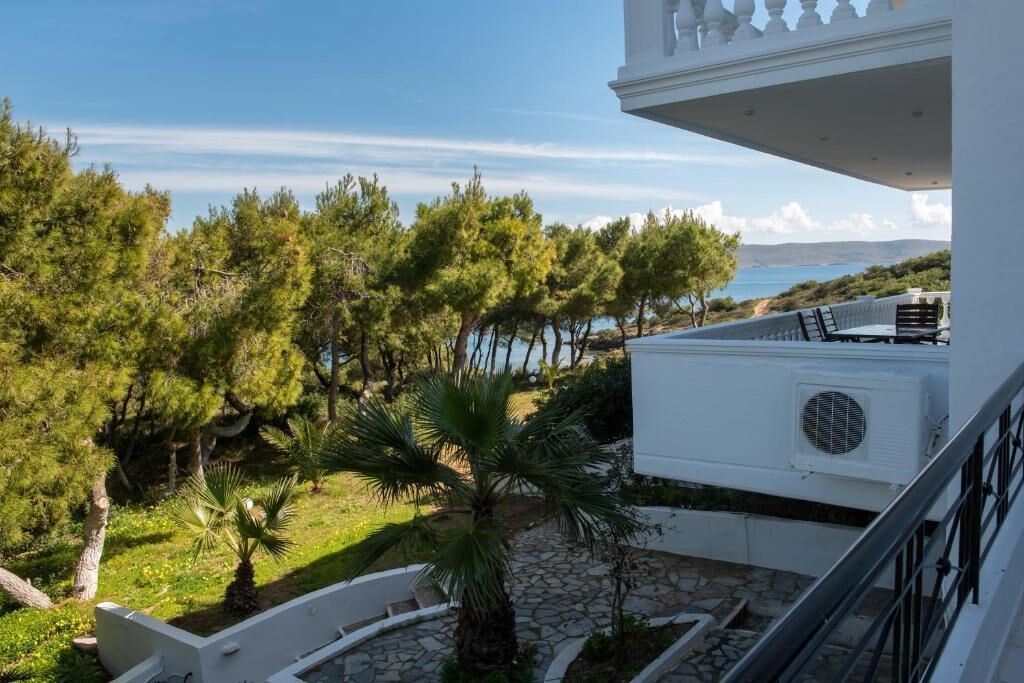 A balcony with a stone pathway, a palm tree, and a view of the sea.