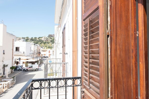 A narrow street with buildings on both sides, a wooden door, and a metal gate.