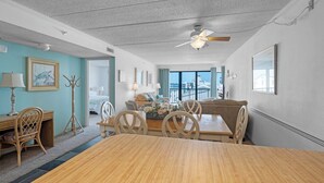 Une pièce comprenant une table à manger en bois, des chaises, un ventilateur de plafond, un lit, une fenêtre avec vue et un bureau avec une lampe.