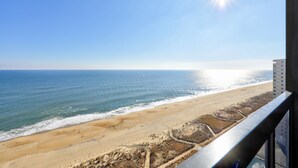 Vista a la playa desde un balcón, cielo despejado y sol brillante.