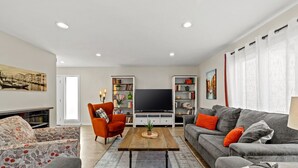 Una sala de estar moderna con un sofá, un sillón, una mesa de centro y un televisor.