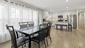 Una cocina moderna con armarios blancos, electrodomésticos de acero inoxidable y una isla central con taburetes.