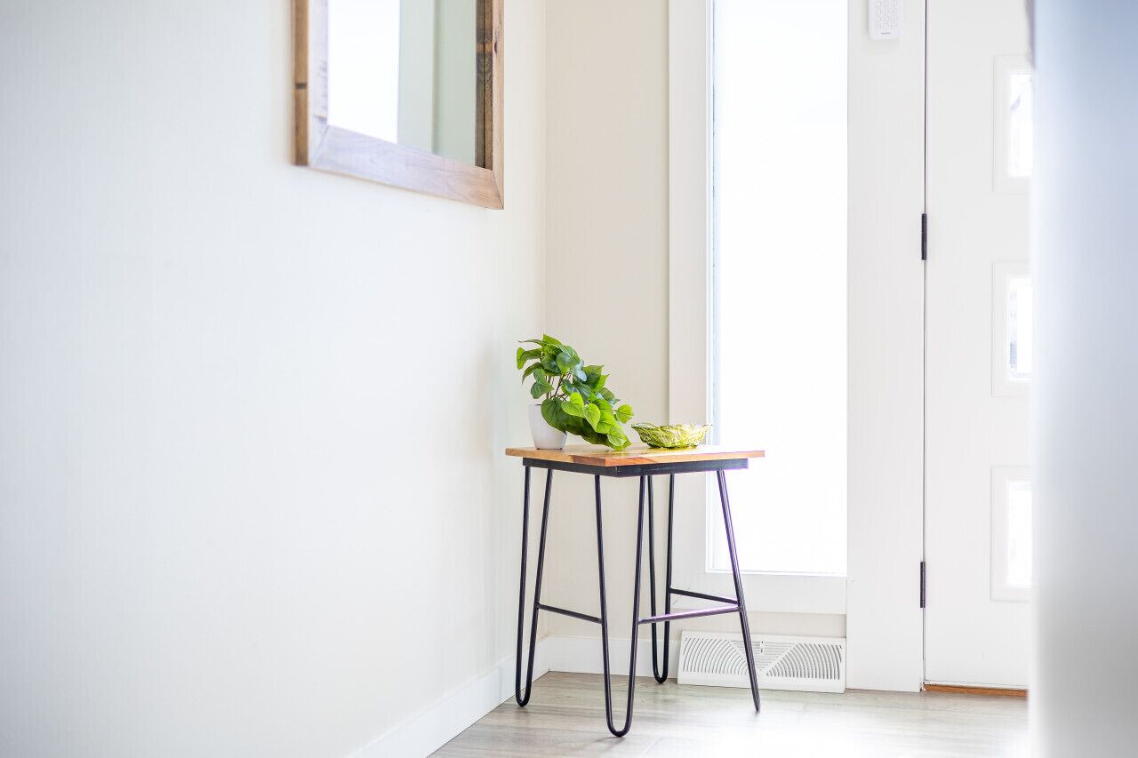 A clean, bright hallway with a wooden table and a potted plant.