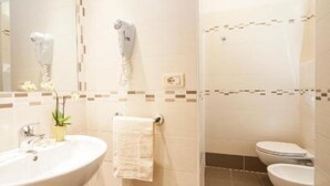 A modern bathroom with a large sink, a mirror, a towel rack, and a toilet. - HOTEL TAORMINA (Riccione)