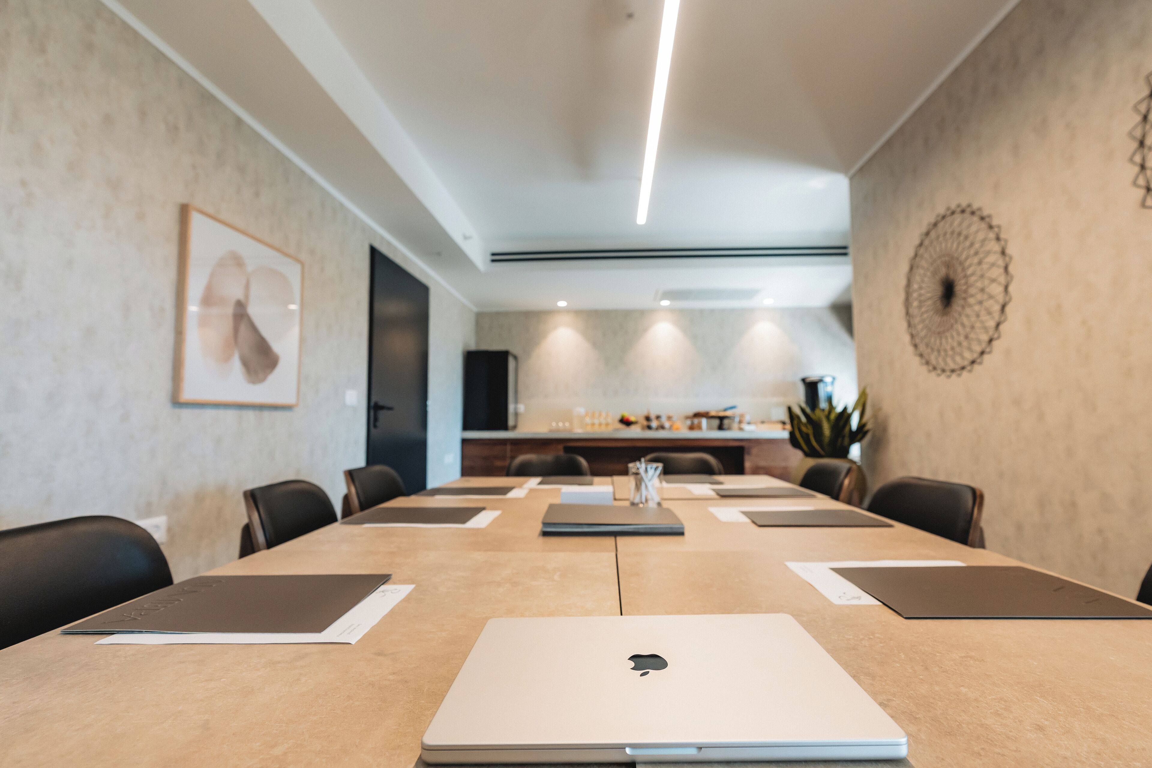 Un salón de conferencias con una larga mesa, computadoras portátiles y sillas.