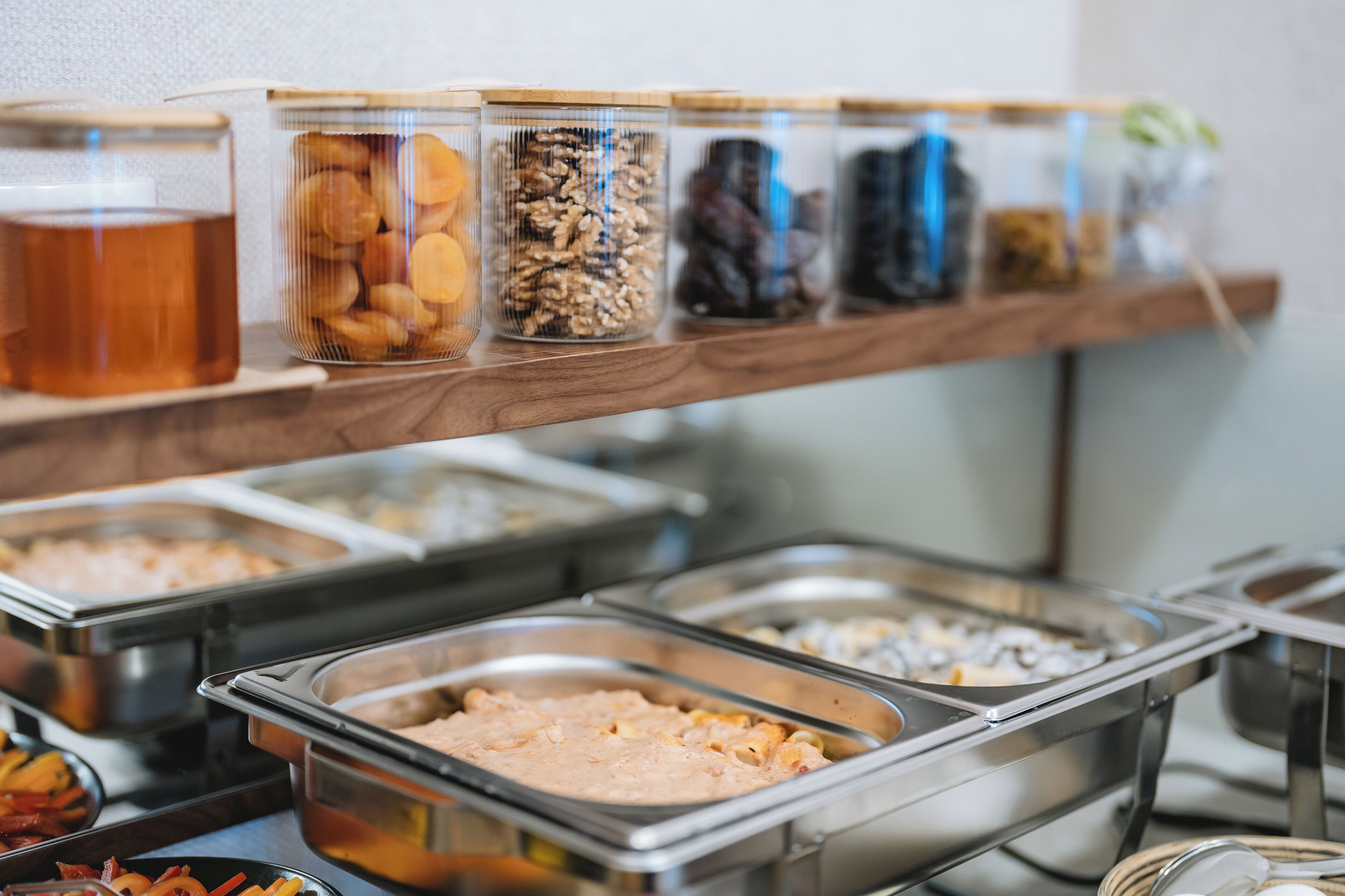A buffet with various food items in clear containers and metal trays.