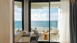 Una habitación moderna con un amplio ventanal que da a un balcón con vista al océano.