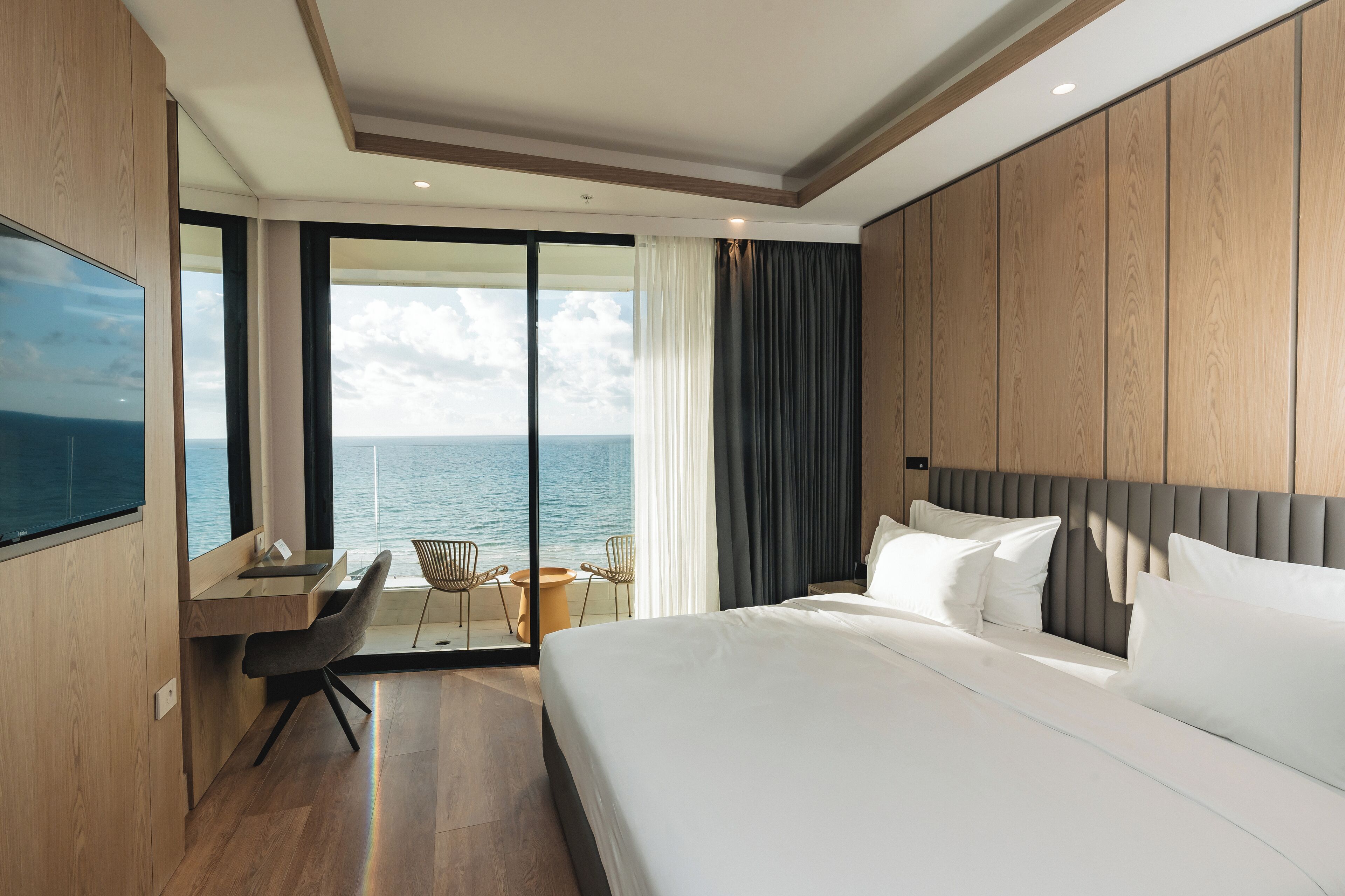 Una habitación de hotel moderna con una cama grande, un escritorio y vistas al océano.